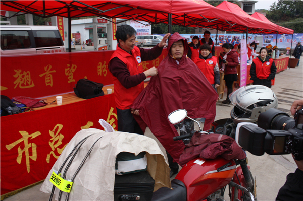 梧州市總工會的黨員義工們在市東出口春運服務(wù)站助力&ldquo;摩托大軍&rdquo;平安返鄉(xiāng)，幫助他們檢查車輛和行李，穿上雨衣。--黃賀峰攝.j